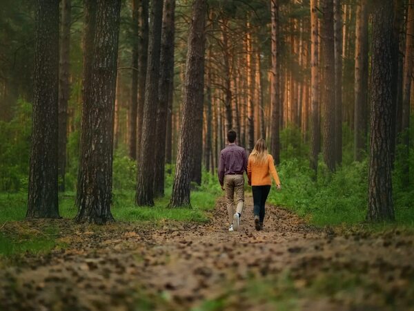 Pessoa adulta a caminhar tranquilamente num caminho rodeado de árvores